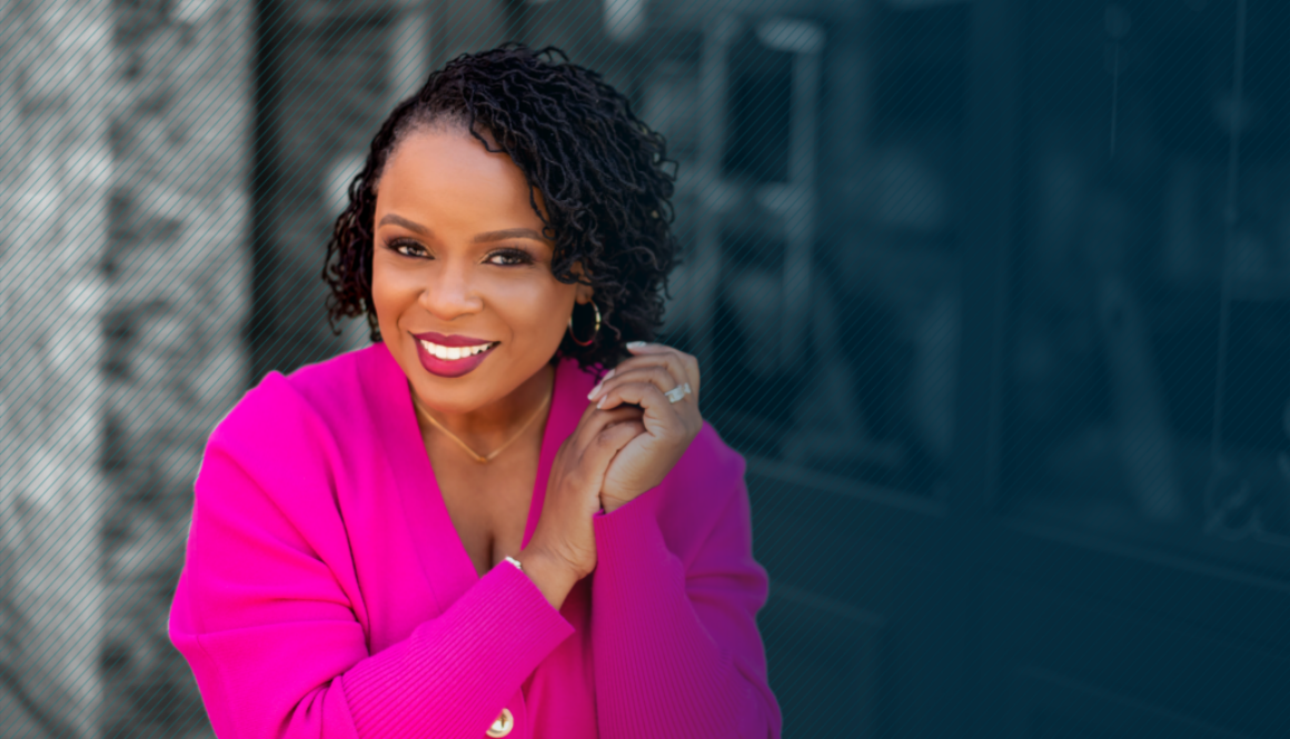 Dr. Amber L. Wright standing on the left side of the frame wearing a pink power suit and looking at the camera with a smile