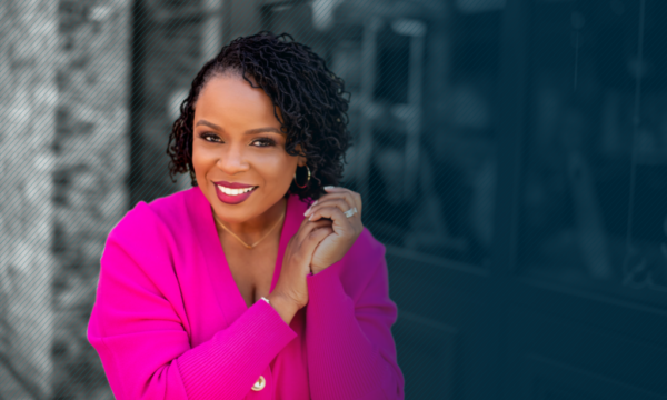 Dr. Amber L. Wright standing on the left side of the frame wearing a pink power suit and looking at the camera with a smile