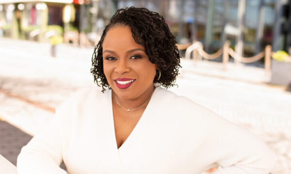 Dr. Amber L. Wright wearing a long sleeved white dress and smiling at the camera