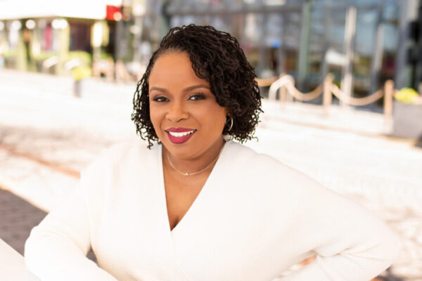 Dr. Amber L. Wright wearing a long sleeved white dress and smiling at the camera